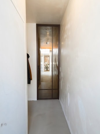 Stalen deur met glazen paneel in een moderne woning, perfect op maat gemaakt voor een strakke en industriële uitstraling.