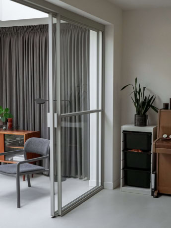 Ruime stalen schuifdeur met glazen panelen in een modern interieur, op maat gemaakt door Aluwdoors.