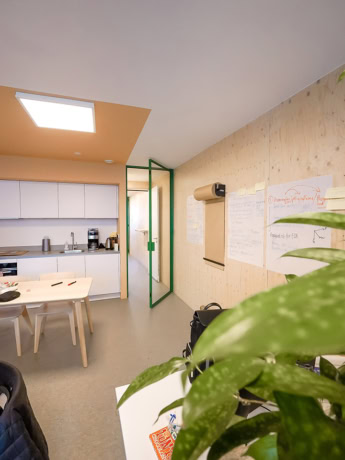 Stalen binnendeur met groene rand in een moderne kantoorruimte.