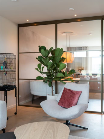 Hoogwaardige stalen deur en wand op maat, moderne binnenruimte met glazen scheidingswand en comfortabele zithoek.