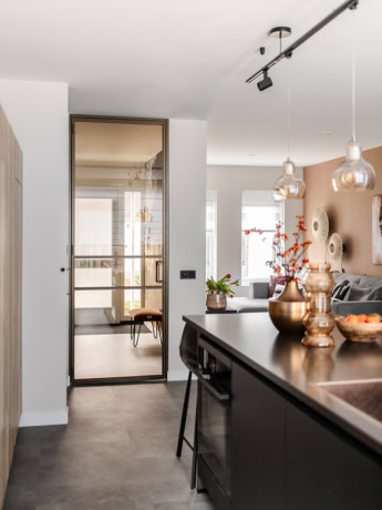 Elegante stalen pendeldeur met glazen panelen voor een moderne binnendeur, geïntegreerd in een luxe woonruimte.