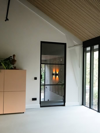 Prachtige stalen scheidingswand met deur op maat in een modern interieur, ideaal voor stijlvolle woningindelingen en kantoorruimtes.