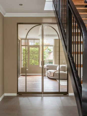 Gezandiseerde stalen deur op maat met glas-in-loodpanelen, ideale scheiding tussen woonkamer en hal, modern industrieel ontwerp, hoogwaardige afwerking.