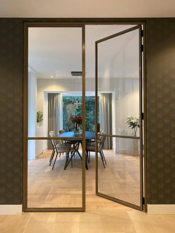 Modern steel sliding door with pedestrian door, perfect for interior partitioning, bespoke steel doors and walls, suitable for various interior styles.