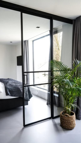 Sleek steel sliding door in a modern interior with large windows and a green plant for a stylish look.