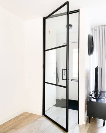 A sleek steel hinged door with glass panels, perfect for modern interiors and bespoke partitions, such as those at Aluwdoors.