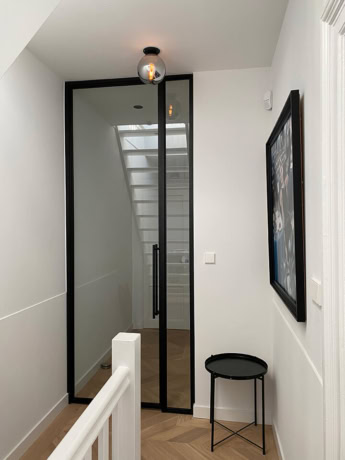 Strakke stalen scharnierdeur met zwart frame en glas, perfect voor moderne interieurs en scheiding van ruimtes.