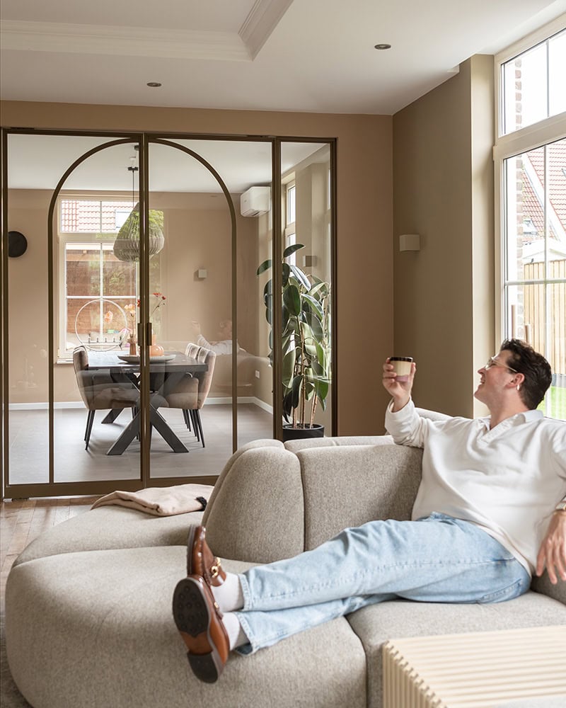 Elegant steel dividing door with glass panels and black frame, separate living and dining room, natural light, modern interior design.