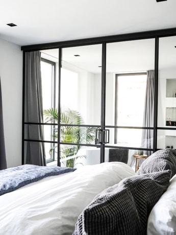 Luxe stalen scheidingswand met glazen panelen in een modern slaapkamer, creëert een elegante en open indeling.