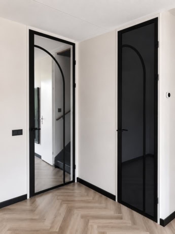 Moderne zwarte stalen opdekdeuren met glazen panelen in een eigentijdse woning, perfect voor stijlvolle binnenafwerking en ruimte-indeling.