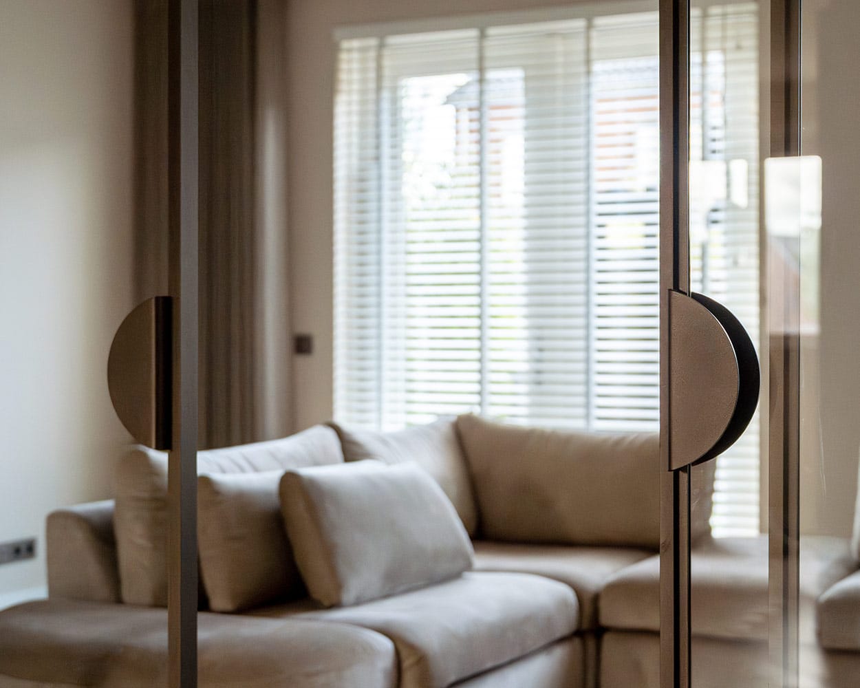 Elegante glazen schuifdeur met zwart metalen frame in een woonkamer, ideaal voor scheiding van ruimtes en modern design, op maat gemaakt door Aluwdoors.