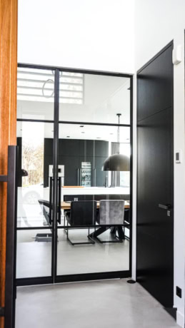 A sleek steel pivot door with glass panels in a modern office, ideal for dividing workspaces and ensuring privacy, made to measure by Aluwdoors.