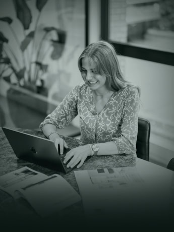 Elegante vrouw werkt op haar laptop in een modern kantoor, omgeven door inspiratie en professionele details.