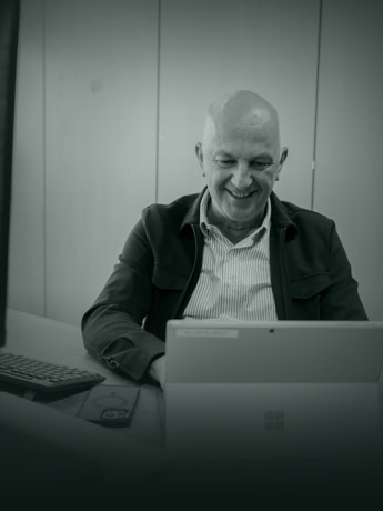 Modern man behind computer with steel door in office.