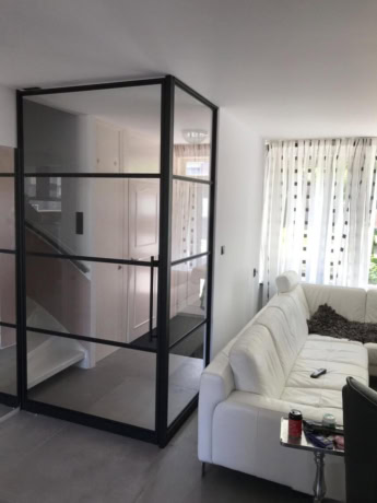 Sleek steel pivot door with glass panels in a modern interior, ideal for room division and a design feature.