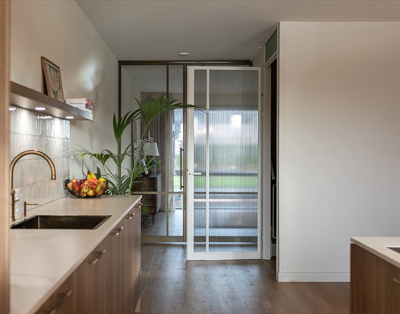 Moderne stalen schuifdeur in een keuken en woonkamer, perfect voor opdekdeuren, met een minimalistisch design en grote glazen panelen voor natuurlijk licht, op maat gemaakt.