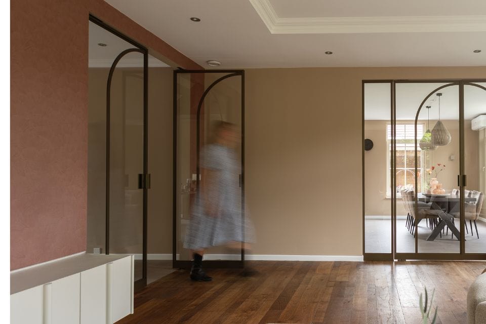 Elegante stalen scheidingswand met moderne glazen deuren in een lichte woonkamer.