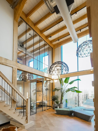 Modern stalen deuren en wanden op maat in een industrieel woon- of werkpand met veel natuurlijk licht en houten details.