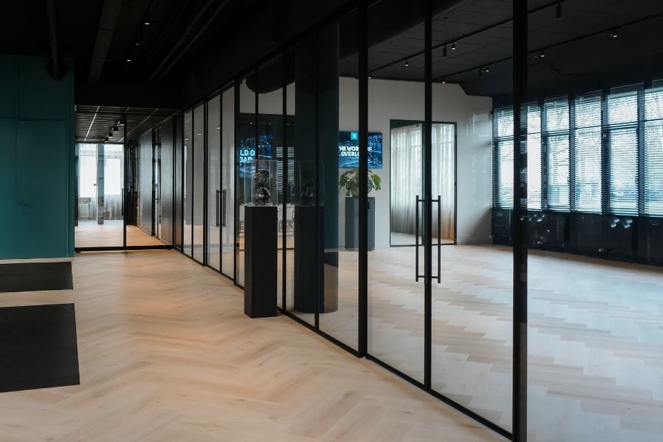 Glass steel partition with black metal frame in modern office interior, suitable for customised partition solutions.