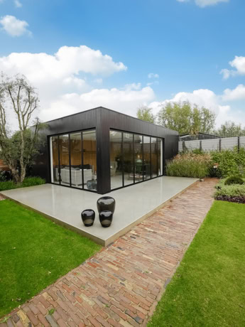 Elegante stalen serre met op maat gemaakte wanden en doorschijnende glazen schuifdeuren voor een moderne uitstraling.