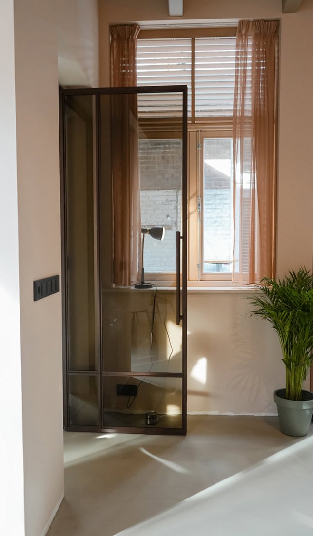 Sophisticated steel interior door with sleek black frame and glass in a modern interior, perfectly tailored by Aluwdoors.