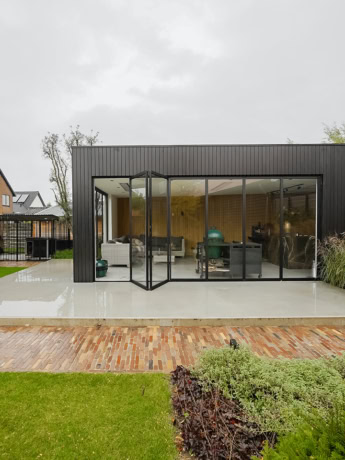 Moderne stalen schuifdeur in een lichte woonruimte met grote raampanelen en zwart metalen frame.