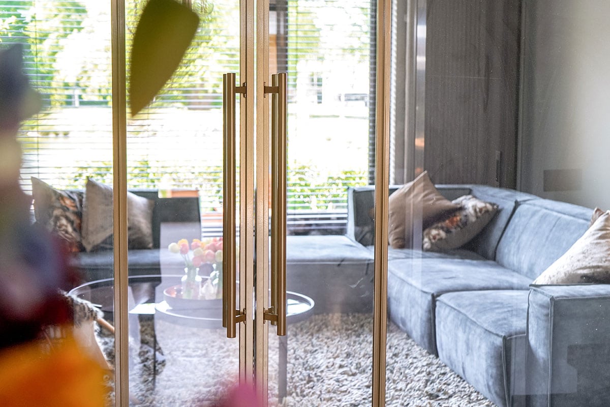 Stevige stalen tuindeur met houten details en grote glazen panelen, vervaardigd op maat door Aluwdoors.