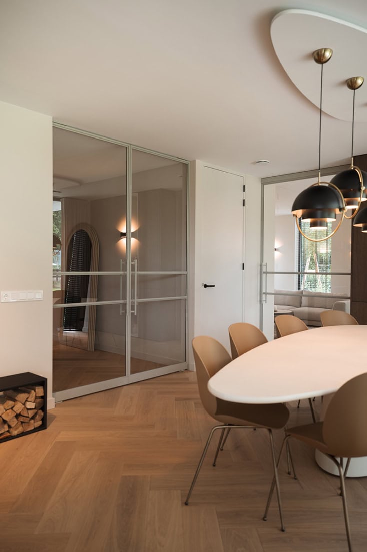 Elevated Scandinavisch interieur met stalen scheidingswand, moderne verlichting en warm houten vloer, accentueert natuurlijke en minimalistische stijl.