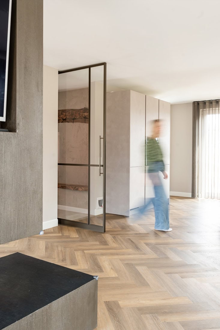 Steel partition door in modern living room with wooden floor and large windows, custom-made steel wall for sleek interior partition.