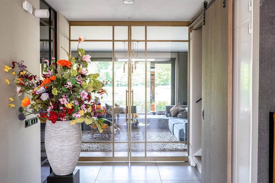 Gidsde stalen schuifdeur met glazen panelen, modern design en op maat gemaakt voor een elegante woonruimte.