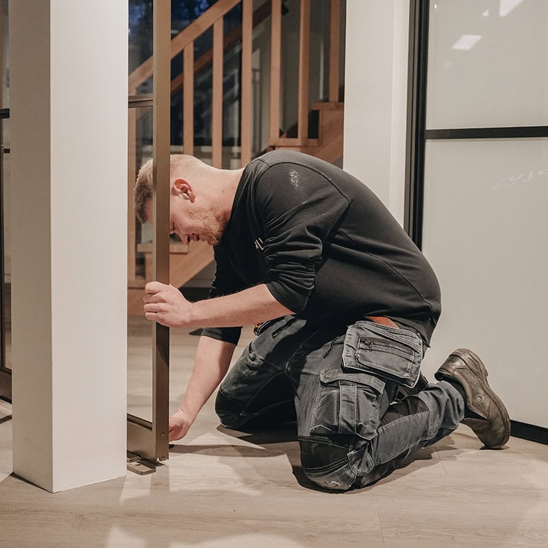 Hij bevestigt een stalen deur of wand, op maat gemaakt en van hoge kwaliteit, binnen een modern interieur.