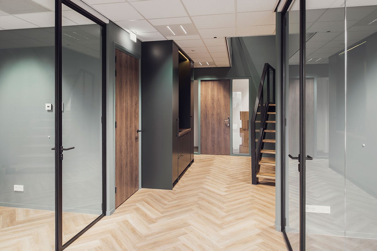 Moderne stalen deur en wanden in een kantoorinterieur met houten vloeren.