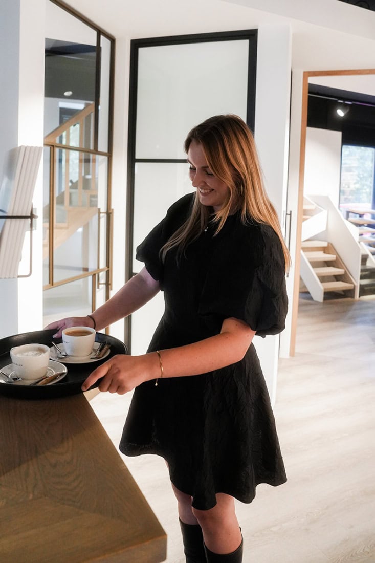 Modern vrouw serveert koffie in een stijlvol interieur met stalen deuren en wanden.