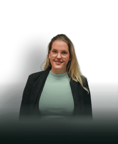 Elegante vrouw met blonde haar en glazen, professioneel in een zwart jasje en mintgroen shirt, staande voor een witte achtergrond met een stijlvol zwart element.