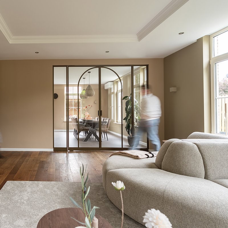 Atmosphere image of high-quality steel partition and custom-made door in modern living room with sliding glass doors and natural light.