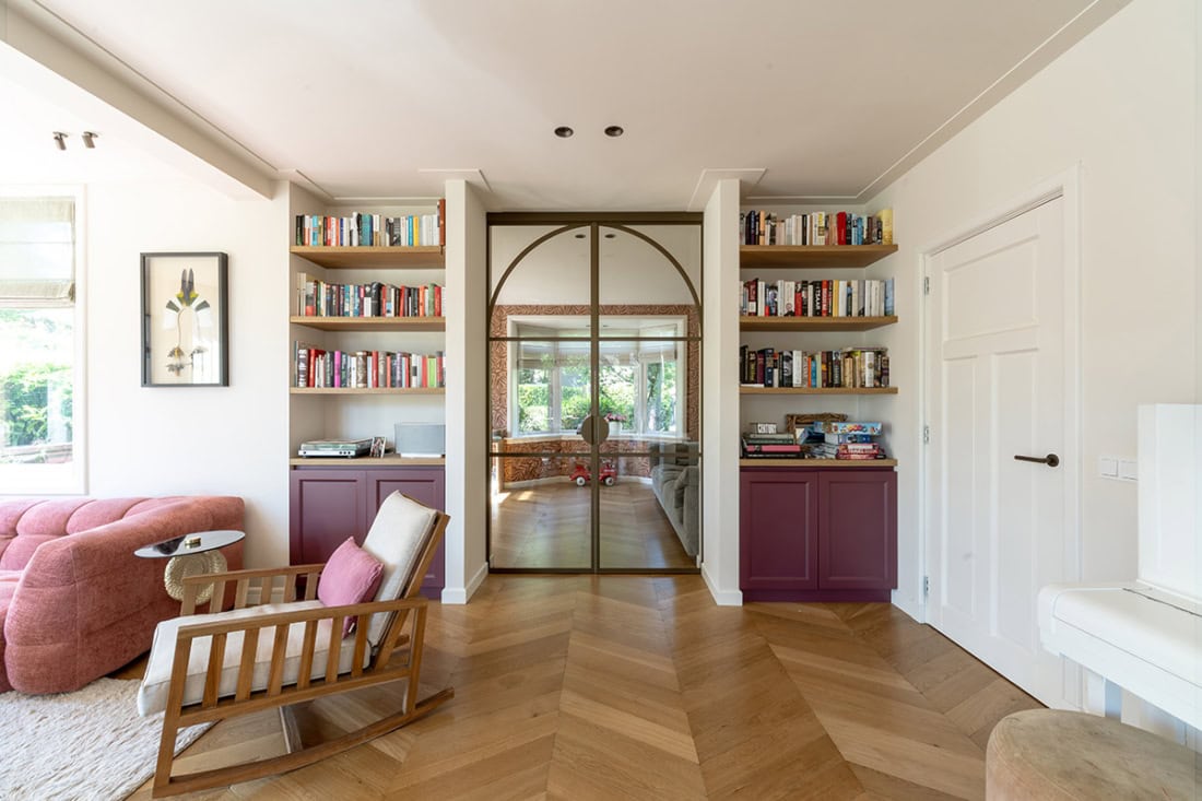 High-quality steel sliding door with glass panels in a modern living room, including bookcases and natural light, custom-made by Aluwdoors.