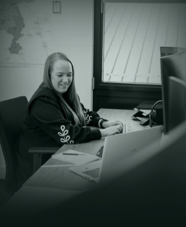 Moderne vrouw werkt aan haar computer in kantoor, omgeven door werkbenodigdheden en een wereldkaart op de achtergrond.