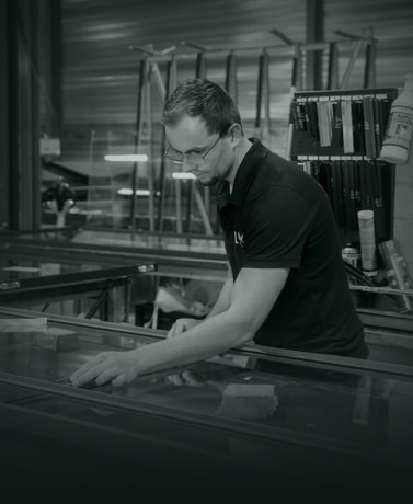 Vakkundige medewerker controleert stalen en onderdelen voor stalen deuren en wanden in productiehal.