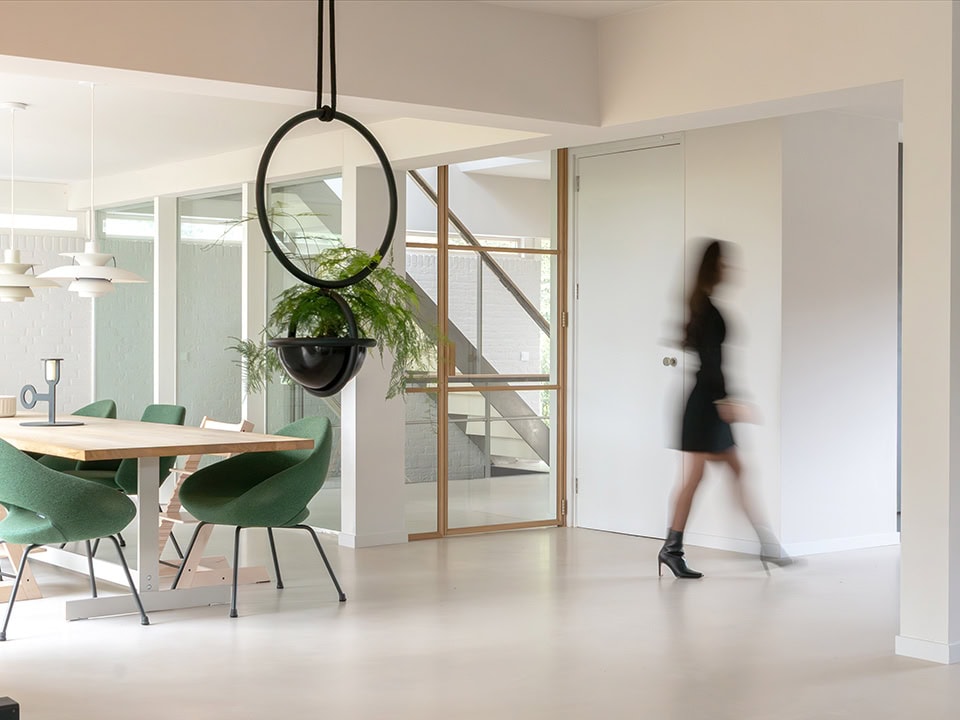 Moderne stalen deur in een eigentijdse woonruimte, met een glazen wand en houten details, passend bij hoogwaardige stalen deuren en wanden op maat.