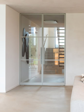 Moderne glazen schuifdeur met stalen frame, perfect voor een strakke en lichte scheiding tussen ruimtes in een woning of kantoor.
