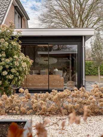 Modern aluminium external facade with large glass panels in a house in Doornspijk, offers plenty of natural light and a clean look, perfect for a stylish outdoor space.