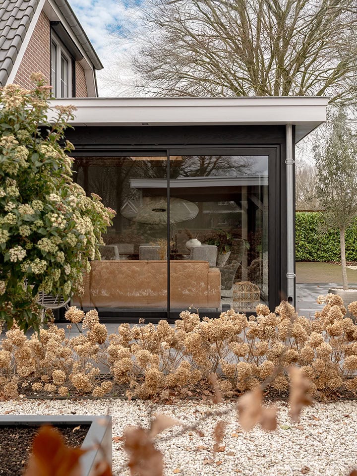 Modern aluminium external facade with large glass panels in a house in Doornspijk, offers plenty of natural light and a clean look, perfect for a stylish outdoor space.