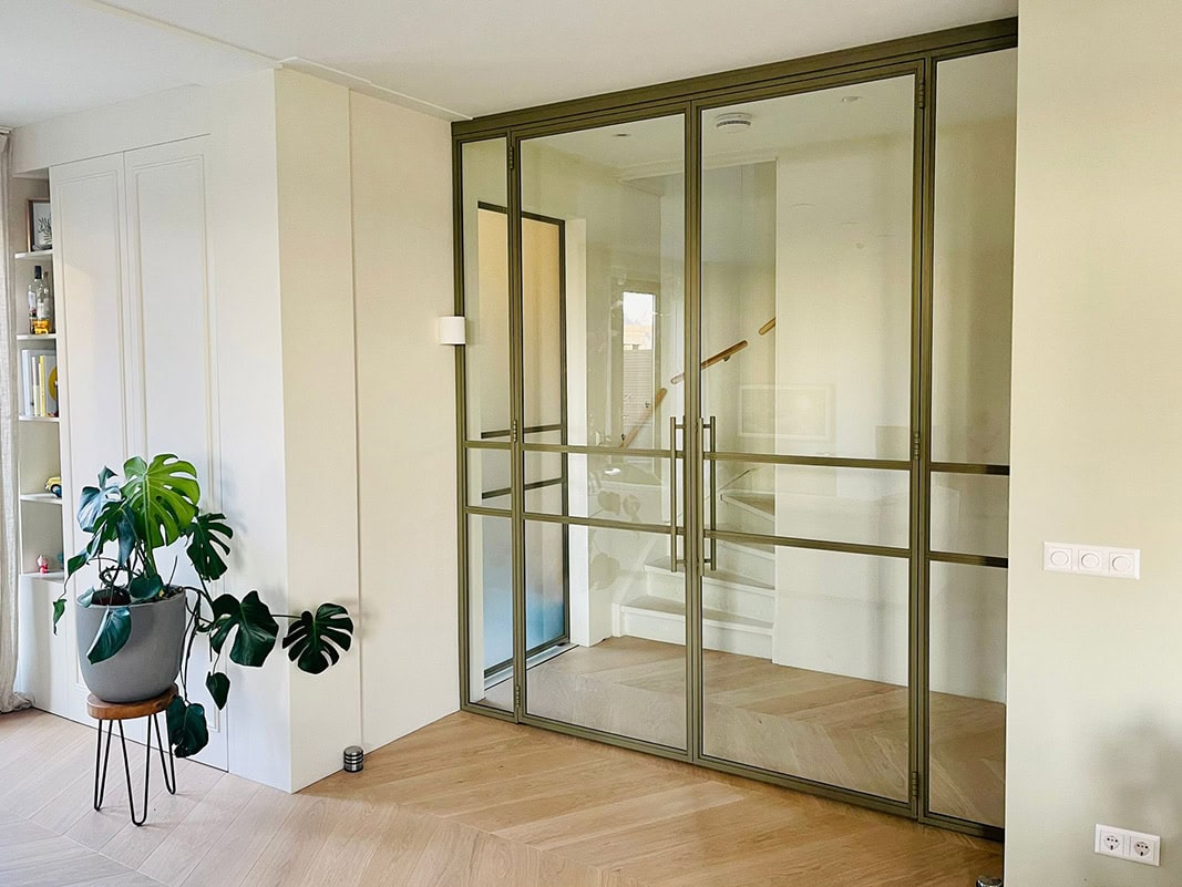 Moderne trapafsluiting met glazen schuifdeur en stalen frame, perfect voor een strakke en veilige scheiding tussen trap en woonkamer, op maat gemaakt door Aluwdoors.