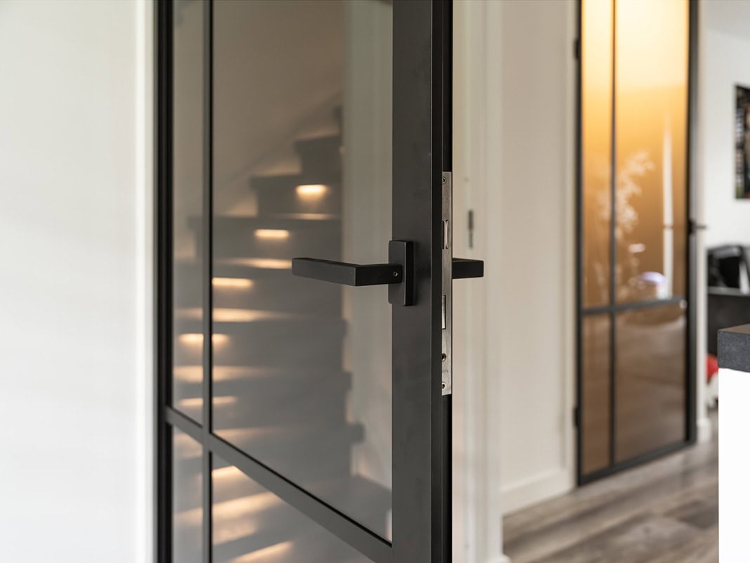 Trapafsluiting met glazen deur en stalen frame, perfect voor het afsluiten van trappen en het creëren van een veilige scheiding in huis. Hoogwaardige afwerking en maatwerk mogelijk.