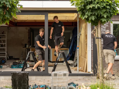 Twee vakbekwame monteurs installeren stalen deuren en wanden op maat bij een nieuwbouwproject, met aandacht voor precisie en vakmanschap.