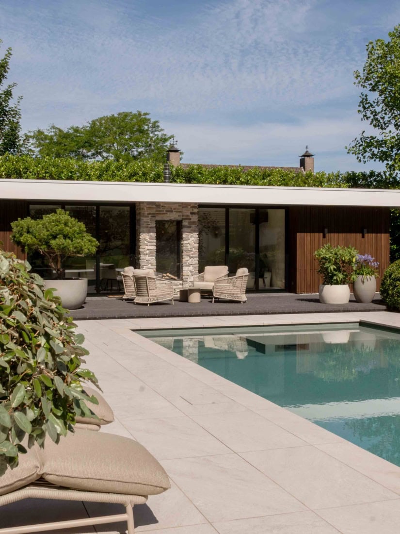 Moderne woning met grote glazen stalen deuren, zwembad en tuin met planten, perfect voor een luxe buitenleven.